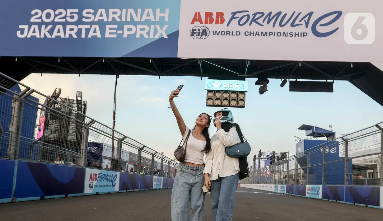 Warga berswafoto di lintasan Formula E World Championship usai menyaksikan sesi Free Practice 1 (FP1) di Jakarta International E-Prix Circuit (JIEC) di Ancol, Jumat (20/6/2025). (Liputan6.com/Herman Zakharia)