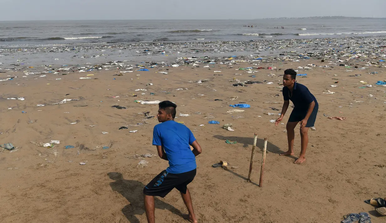 Dua pemuda India bermain kriket dengan dipenuhi sampah plastik di pantai Juhu di Mumbai, (2/6). (AFP PHoto/Punit Paranjpe)