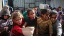 Terhambatnya peningkatan bantuan ke Gaza disebabkan beberapa faktor di antaranya, pembatasan visa, persetujuan impor, minimnya titik penyeberangan, serta berbagai hambatan teknis dan administratif lainnya. Tampak dalam foto, warga Palestina yang terlantar, anak-anak, dan dewasa, menunggu makanan di sebuah tempat penampungan yang telah dihuni keluarga-keluarga di Nuseirat, pusat Jalur Gaza, pada 23 November 2025. (EYAD BABA/AFP)