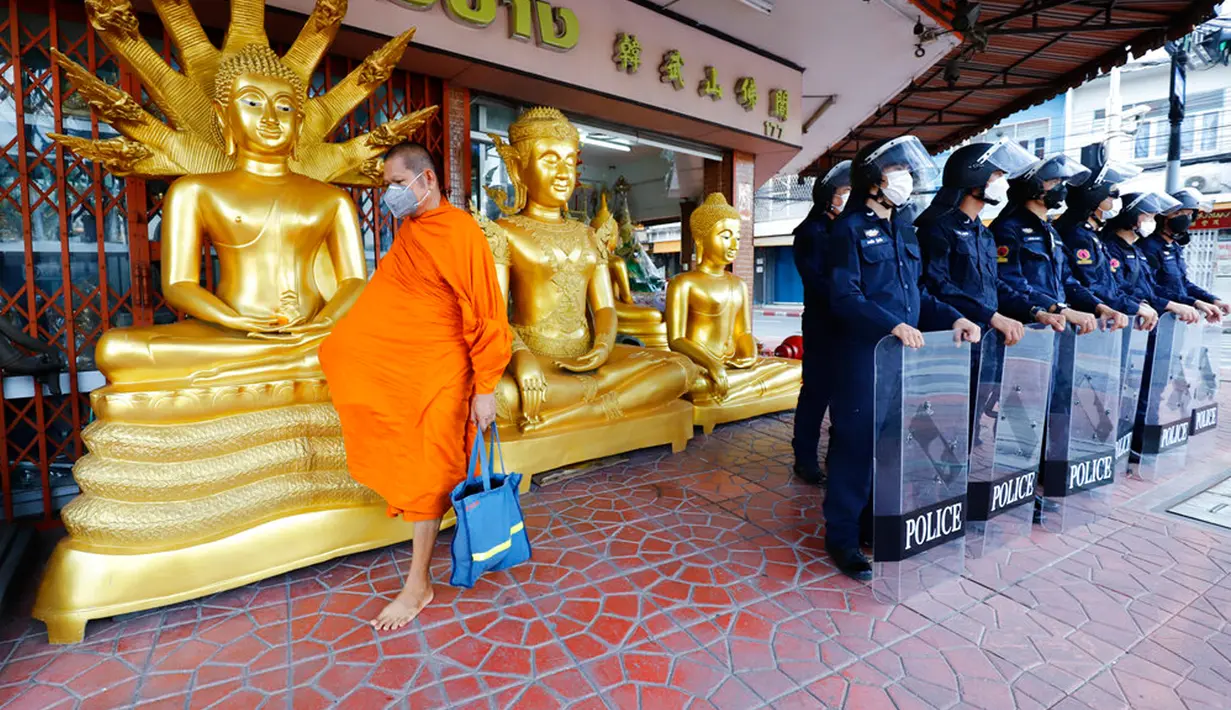 Seorang biksu Buddha berjalan melewati polisi antihuru-hara dekat tempat KTT APEC di Bangkok, Thailand, Jumat (18/11/2022). KTT APEC yang berlangsung pada tanggal 18-19 November 2022 diwarnai aksi unjuk rasa. (AP Photo/Sarot Meksophawannakul)
