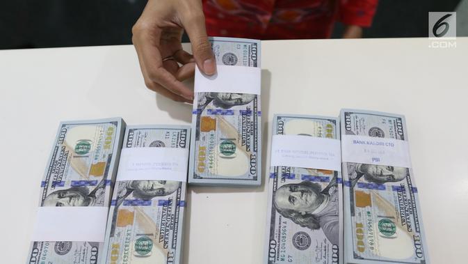 Teller menunjukkan mata uang dolar di Bank Mandiri, Jakarta, Kamis (10/1). Nilai tukar rupiah terhadap dolar Amerika Serikat (AS) terus menguat di perdagangan pasar spot hari ini. Rupiah berada di zona hijau. (Liputan6.com/Angga Yuniar)