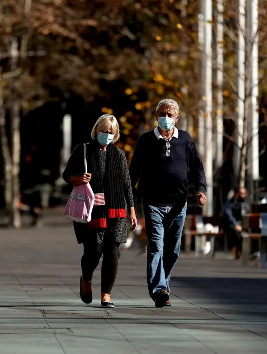 Orang-orang berjalan di sekitar Circular Quay, Sydney, Australia, Selasa (13/7/2021). Lima juta penduduk Sydney akan berada dalam lockdown COVID-19 untuk dua minggu lagi. (Brendon THORNE/AFP)