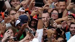 Lewis Hamilton berselebrasi bersama pendukungnya usai meraih kemenangan GP Italia di Sirkuit Monza di Monza, (2/9). Hamilton berhasil menang di GP Italia 2018 dengan catatan waktu terbaik 1 jam 16 menit 54,484 detik. (AP Photo/Luca Bruno)