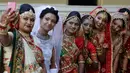 Sejumlah pengantin perempuan foto bersama saat nikah massal di Surat, India, Minggu (23/12). Pernikahan di India adalah urusan mahal. (AP/Ajit Solanki)