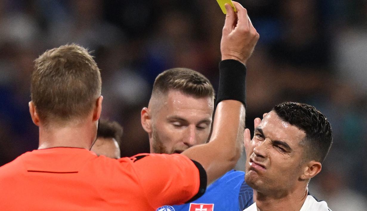 Pemain Portugal, Cristiano Ronaldo (kanan) mendapatkan kartu kuning dari wasit setelah melakukan pelanggaran terhadap kiper Slovakia, Martin Dubravka saat laga grup G Kualifikasi Euro 2024 di National Football Stadium in Bratislava, Slovakia, Sabtu (9/9/2023) dini hari WIB. (AFP/Vladimir Simicek)