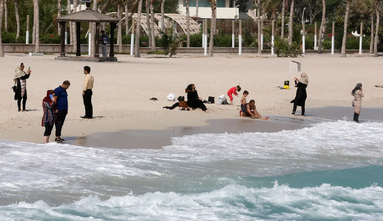Turis bersantai di pinggir pantai, Pulau Kish di Iran, 1 November 2016. Pantai Kish yang terletak di kawasan pesisir Iran ini berjarak hanya 200 kilometer dari Dubai. (Atta Kenare/AFP)