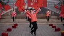 Kelompok Serikat Wanita Sosialis mengibarkan bendera saat melakukan propaganda di depan Hotel Ryugyong, Pyongyang, Korea Utara, Sabtu (9/3). Kehadiran mereka dimaksudkan untuk memotivasi para pekerja agar lebih semangat. (Ed Jones/AFP)