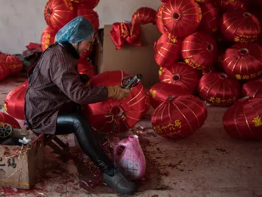 Seorang pekerja sedang membuat lampion merah menjelang perayaan Tahun Baru Imlek di provinsi Hebei, Tingkok (11/1). Jelang perayaan Imlek yang jatuh pada 15 Februari, warga setempat disibukan dengan pembuatan lampion. (AFP Photo/Fred Dufour)