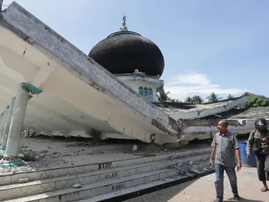 Warga melintas di depan masjid yang roboh usai gempa di Meuredu, Pidie Jaya, Aceh, Rabu (7/11). Selain meruntuhkan bangunan, gempa bumi berkuatan 6,4 SR ini telah menelan banyak korban jiwa. (Antara Foto / Irwansyah Putra / via REUTERS)
