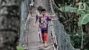 Anak-anak melintasi jembatan gantung yang sudah tidak layak di kawasan Srengseng Sawah, Jakarta, Sabtu (12/6/2021). Jembatan gantung di atas Sungai Ciliwung tersebut saat ini dalam kondisi tidak layak dan dapat membahayakan keselamatan warga yang melintas. (merdeka.com/Iqbal S. Nugroho)