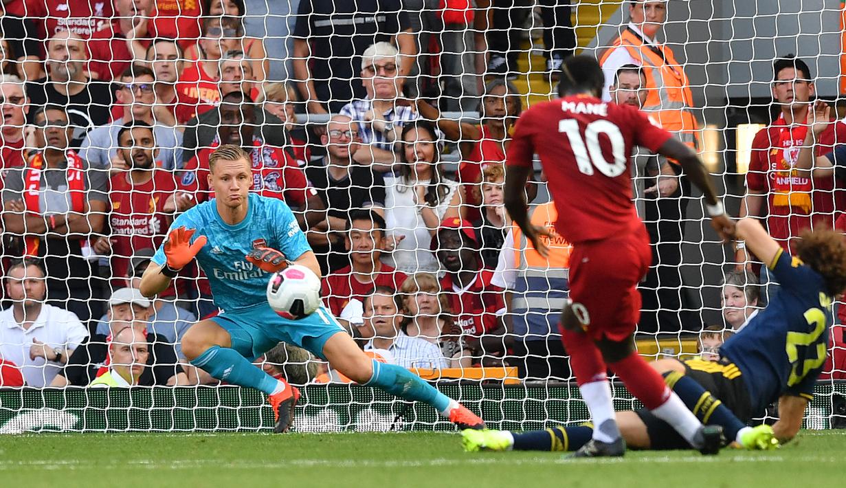 Kiper Arsenal Bernd Leno (kiri) menghalau tendangan striker Liperpool Sadio Mane (kanan) saat bertanding dalam Liga Inggris di Stadion Anfield, Liverpool, Inggris, Sabtu (24/8/2019). Liverpool menang 3-1 dan kukuh di puncak klasemen sementara. (BEN STANSALL/AFP)