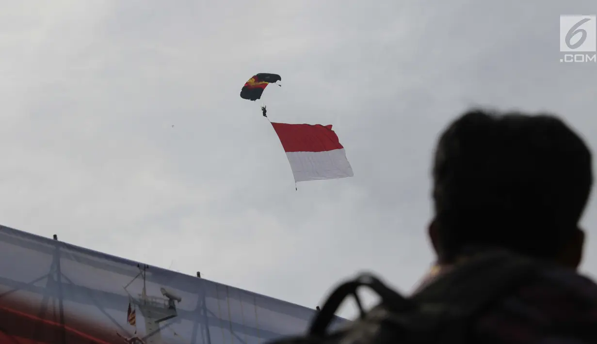 Prajurit Polairud melakukan aksi terjun payung sambil membentangkan bendera Merah Putih pada peringatan Hari Ulang Tahun (HUT) ke-67 Korps Polisi Air dan Udara di Lapangan Udara Pondok Cabe, Tangerang Selatan, Selasa (5/12). (Liputan6.com/Faizal Fanani)