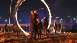 Warga Korea Selatan memutar kaleng arang yang terbakar selama perayaan  Bulan Purnama pertama tahun baru Imlek di Seoul (17/2). Permainan ini dipercaya dapat menyuburkan tanah dan menyingkirkannya hama. (AFP Photo/Jung Yeon-je)