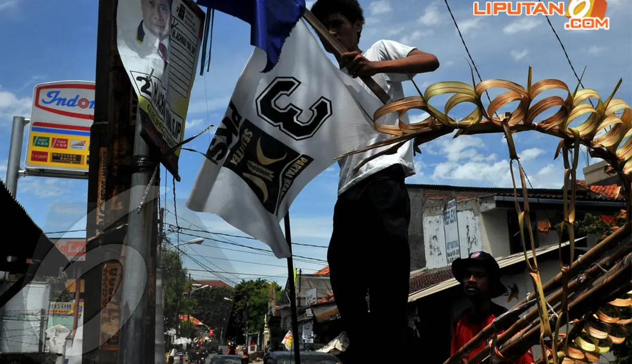  Bendera-bendera partai yang masih bertengger di tiang listrik dibersihkan oleh petugas Pemda di kawasan Mampang (7/4/2014) (Liputan6.com/Johan Tallo).