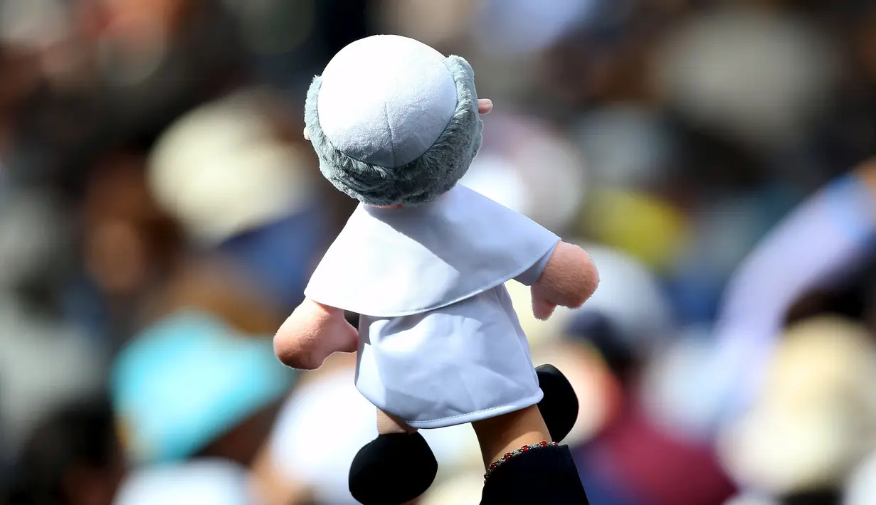 Seorang wanita memegang boneka menyambut kedatangan Paus Fransiskus di Universitas Katolik, Quito,Ekuador,(7/ 7/2015). Paus Fransiskus membahas tentang keadilan sosial dan keseimbangan sumber daya bumi. (REUTERS/Alessandro Bianchi)