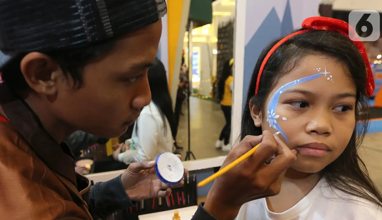 Pengunjung sedang body painting pada wajah pada ICEFEST 2019 di BSD Tangerang, Kamis (19/12/2019). ICEFEST 2019 hadir mengangkat kisah persahabatan ILO dan Aiden di desa Happy Village yang diharap dapat memberikan edukasi yang dikemas dengan hiburan kepada anak-anak. (Liputan6.com/Fery Pradolo)