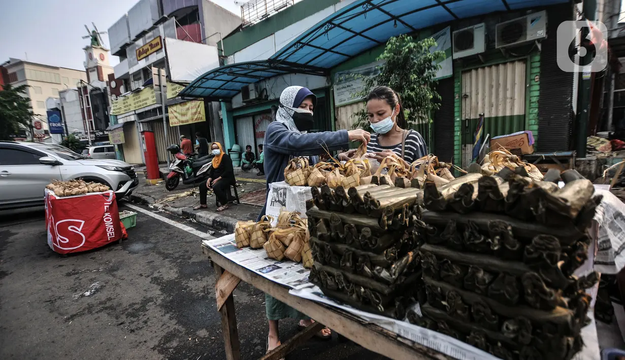 Pedagang melayani pembeli ketupat matang di jalan kawasan Rawamangun, Jakarta, Senin (19/7/2021). Jelang Hari Raya Idul Adha, pedagang ketupat matang atau siap saji musiman mulai ramai menjajakan makanan khas Lebaran tersebut di pinggir jalan kawasan Rawamangun. (merdeka.com/Iqbal S. Nugroho)