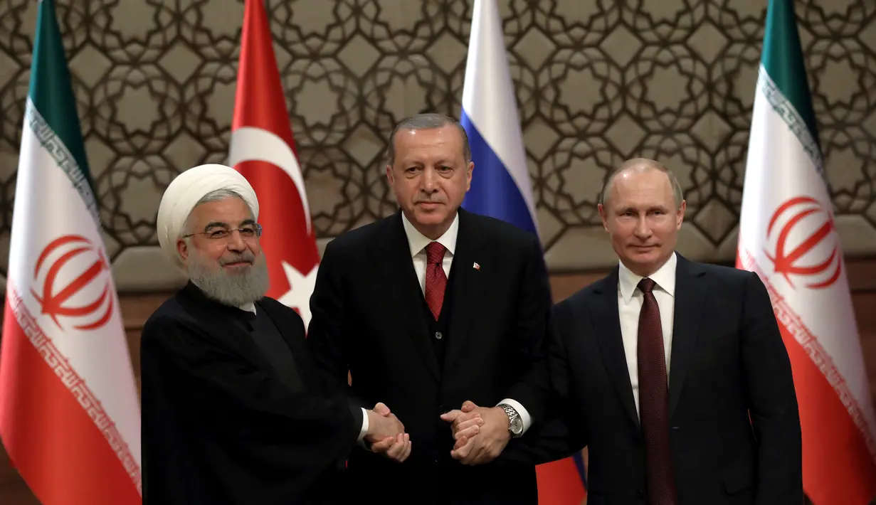 Presiden Turki Recep Tayyip Erdogan (tengah) bersama Presiden Rusia Vladimir Putin (kanan) dan Presiden Iran Hassan Rouhani (kiri) bergandengan tangan setelah konferensi pers bersama di Ankara, Turki, Rabu (4/4). (AP Photo/Burhan Ozbilici)