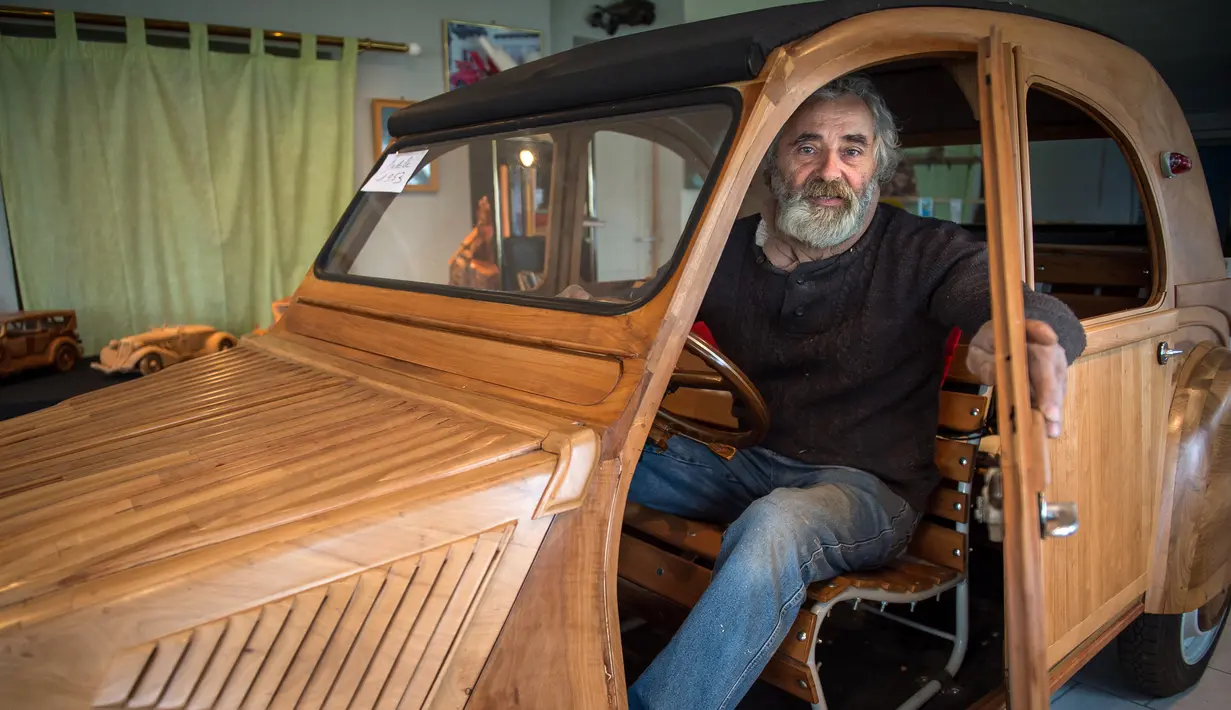 Seorang pensiunan tukang lemari, Michael Robillard, duduk di replika mobil legendaris Citroen 2CV dari kayu di bengkel kerjanya di Loches, Prancis, 21 Maret 2017. Mobil klasik itu dibuat dengan skala sesungguhnya atau 1:1. (GUILLAUME SOUVANT/AFP)