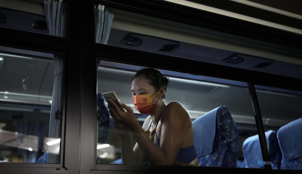 Wang Fan asal Tiongkok, berinteraksi dengan telepon selular saat berada di dalam bus usai pertandingan voli pantai putri Olimpiade Tokyo 2020 melawan Brasil, Selasa (27/7/2021). (Foto: AP/Felipe Dana)