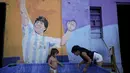 Seorang gadis menyegarkan diri di kolam anak-anak di luar rumahnya dengan mural mendiang pemain sepak bola Diego Maradona di Buenos Aires, Argentina, Kamis, 2 Maret 2023. (AP Photo/Natacha Pisarenko)