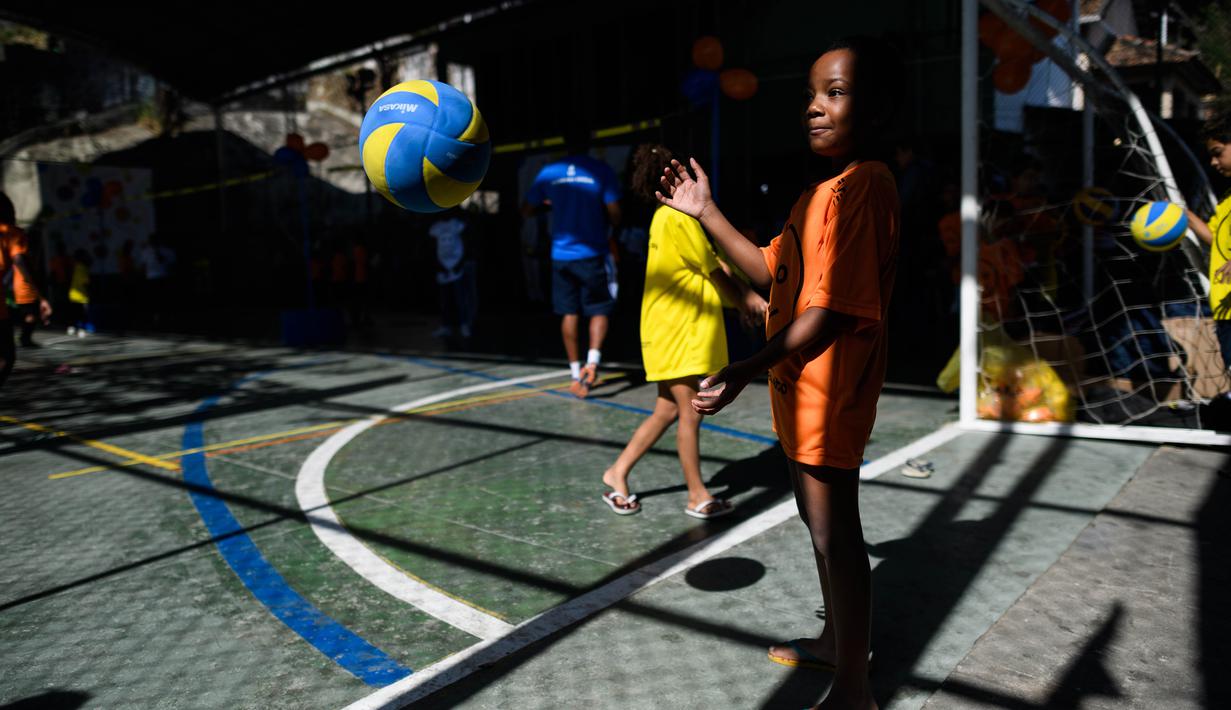 Seorang anak sedang mencoba memukul bola voli pada program Volleyball Development Training yang digagas oleh Federasi Bola Voli Internasional di Formiga favela, Rio de Janeiro, (2/8/2016). (AFP/Leon Neal)