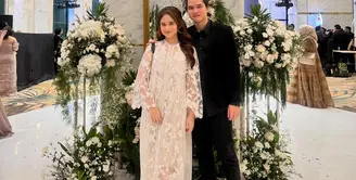 Gaya manis pasangan Dul Jaelani dan Tissa Biani saat kondangan. Tissa Biani tampil cantik dengan dress lace berwarna putih, sedangkan Dul tampil serba hitam dengan kemeja lengan panjang berwarna hitam dan celana panjangnya. [Foto: Instagram/tissabiani]