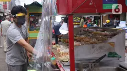 Pedagang mengenakan face sheild atau pelindung wajah saat berjualan di Tangerang, Banten, Rabu (13/5/2020). Penggunaan pelindung wajah tersebut dilakukan untuk mencegah risiko penularan virus corona COVID-19 pada saat berdagang. (Liputan6.com/Angga Yuniar)