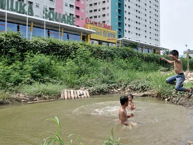 Anak-anak berenang di kubangan air di depan Apartemen Green Pramuka, Jakarta, Rabu (5/2/2020). Keterbatasan ekonomi dan minimnya lahan bermain membuat sekelompok anak sekolah dasar ini memilih berenang di kubangan meskipun mereka tahu air kotor dapat menimbulkan penyakit. (merdeka.com/Iqbal Nugroho)
