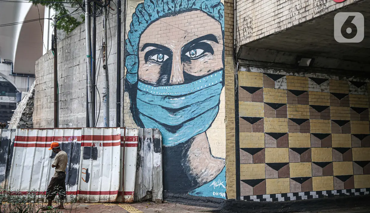 Pejalan kaki melintas dekat lukisan mural melawan COVID-19 di Kawasan Cikokol, Cawang, Jakarta, Minggu (4/10/2020).  Mural masih dianggap menjadi sarana edukasi kesehatan yang tepat bagi warga untuk menjaga diri dari penularan virus Covid 19. (Liputan6.com/Faizal Fanani)