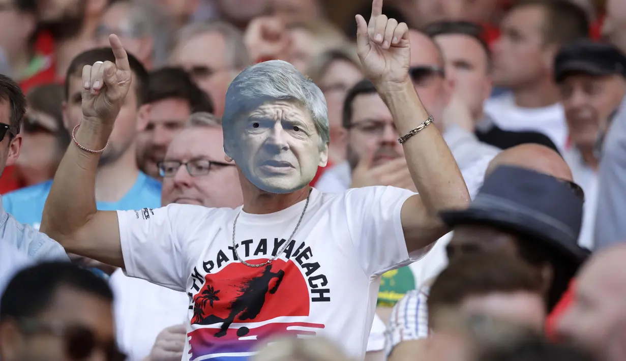 Seorang fans menggunakan topeng wajah Arsene Wegner saat laga Arsenal melawan Burnley di Emirates Stadium, London, (6/5/2018). Arsene Wegner mengumumkan mundur sebagai pelatih setelah 22 tahun bersama Arsenal. (AP/Matt Dunham)
