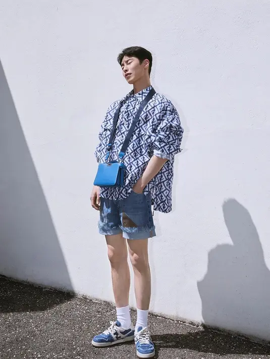 Lee Jae Wook dalam balutan one brand outfit. Ia mengenakan oversized shirt bernuansa biru dengan corak logo brand, dipadunya dengan denim short pants, kaus kaki putih, dan sneakers yang juga bernuansa biru senada. [Foto: Instagram/jxxvvxxk]
