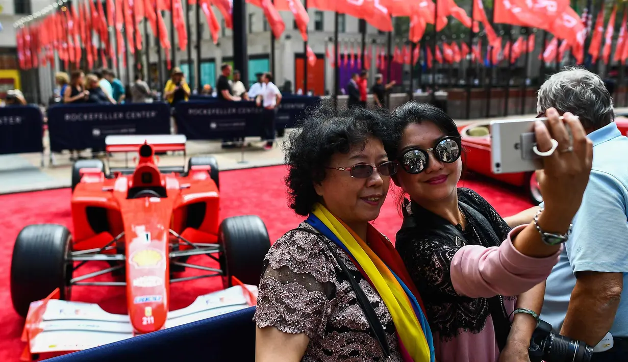 Dua wanita berselfie dengan latar mobil mantan pembalap Ferrari F1, Michael Schumacher di Rockefeller Plaza, New York, AS (8/10). Mobil tersebut pernah memenangkan salah satu seri balapan F1 di Grand Prix Monaco pada tahun 2001. (AFP Photo/Jewel Samad)