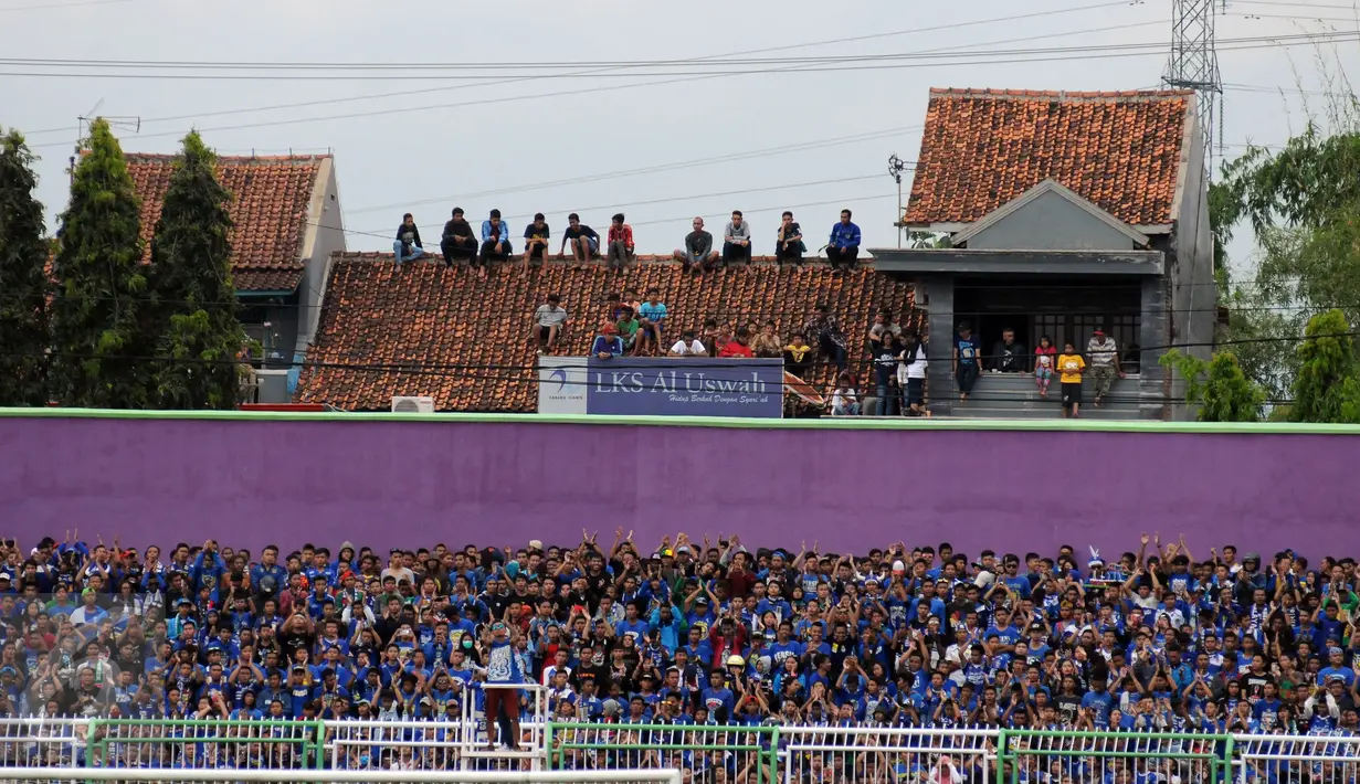 Ribuan suporter tim Maung Bandung duduk di atas atap sebuah rumah untuk menyaksikan laga antara Persib melawan PSGC di Stadion Galuh Ciamis, Minggu (10/4/2016). Persib unggul 5-1 atas PSGC. (Liputan6.com/Helmi Fithriansyah)