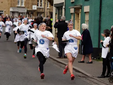 Para peserta bersaing dalam lomba lari sembari membawa wajan berisi pancake di Kota Olney, Buckinghamshire, Inggris, Selasa (28/2). Tidak hanya membawa wajan, peserta juga harus membolak-balikan pancake sambil tetap berlari.  (AP Photo/Alastair Grant)