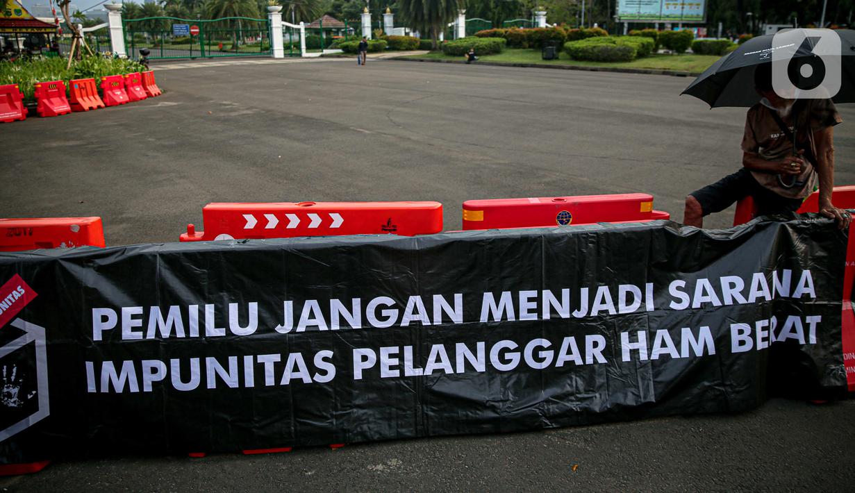 Poster bertuliskan "Pemilu Jangan Menjadi Sarana Impunitas pelanggaran HAM Berat" saat anggota Jaringan Solidaritas Korban untuk Keadilan (JSKK) melakukan Aksi Kamisan ke-795 di seberang Istana Merdeka, Jakarta, Kamis (16/11/2023). (Liputan6.com/Faizal Fanani)