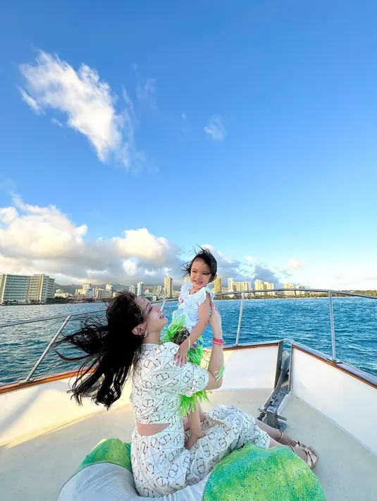 Outfit lainnya di atas kapal, Shandy Aulia kenakan back cutout dress yang feminin. Dipangku sang ibu, Claire terlihat cantik dengan dress putih [@shandyaulia]