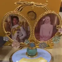 Box pertama berisikan pajangan foto dengan desain keemasan dan pita di bagian atas, lalu di bagian bawah terdapat aksen bunga warna pastel. Panjang tersebut diisi dengan foto kedua mempelai. [@littleummi.bn]