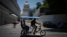 Seorang penumpang mengendarai taksi sepeda melewati Capitol di Havana, Kuba, Selasa (17/5/2022). Pemerintahan Presiden AS, Joe Biden mengumumkan akan melonggarkan pembatasan atas pengetatan yang diberlakukan selama pemerintahan Donald Trump terhadap Kuba dan mencabut batas saat ini $1.000 per kuartal yang dapat dikirim imigran kepada anggota keluarga yang masih tinggal di pulau itu. (AP Photo/Ramon Espinosa)
