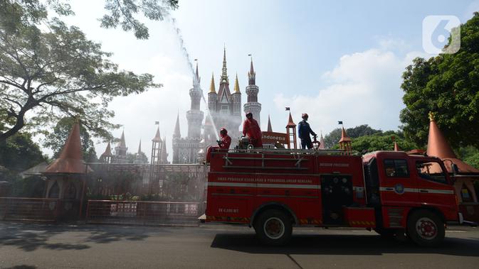 Petugas pemadam kebakaran melakukan penyemprotan cairan disinfektan tempat wisata di Taman Mini Indonesia Indah (TMII), Jakarta, Rabu (10/6/2020). Rencananya, TMII kembali dibuka untuk umum pada 20 Juni 2020 dengan menerapkan tatanan kenormalan baru. (merdeka.com/Imam Buhori)