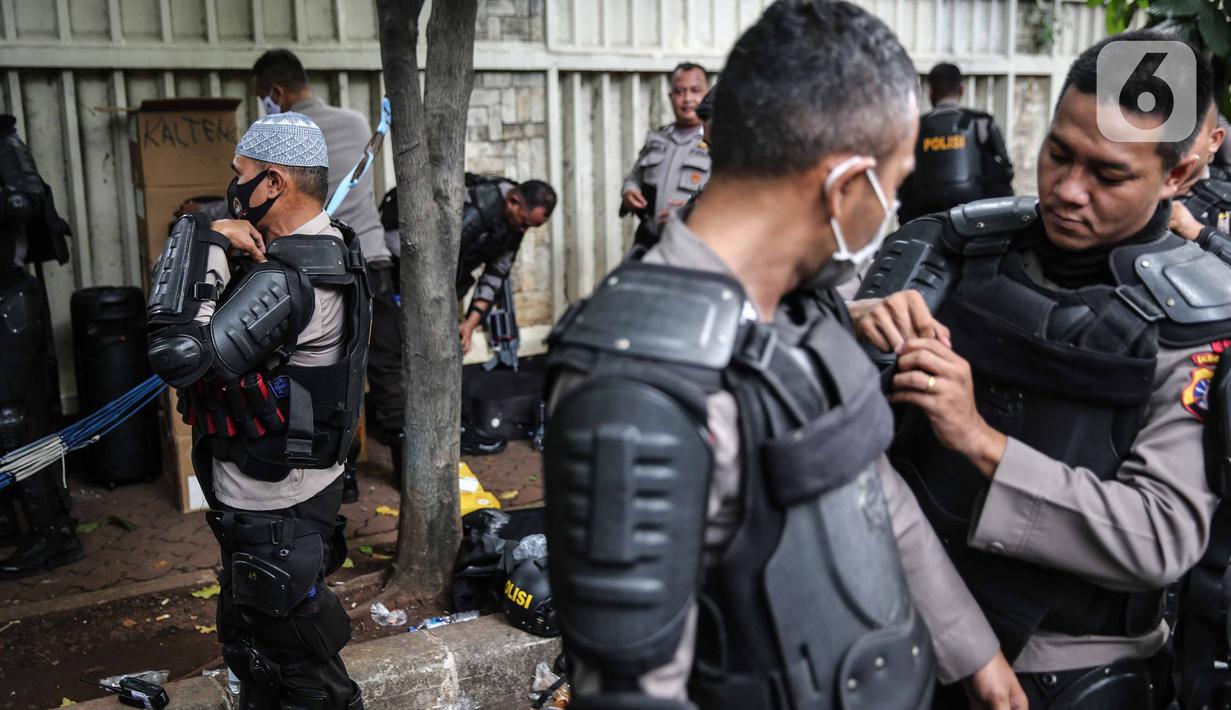 Personel Brimob bersiap mengenakan perlengkapan pelindung diri di Kawasan Bundaran HI, Jakarta, Selasa (13/10/2020). Sebanyak kurang lebih 12 ribu personel gabungan TNI, Polri dan Pemprov DKI Jakarta diterjunkan mengawal aksi tolak Undang-Undang Cipta Kerja Omnibus Law. (Liputan6.com/Faizal Fanani)