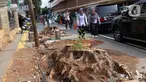 Pejalan kaki melintas di sisi sisa pohon yang ditebang untuk revitalisasi trotoar di kawasan Cikini, Jakarta, Kamis (21/11/2019). Setiap 21 November diperingati sebagai Hari Pohon Sedunia, hal ini untuk mengingatkan masyarakat akan manfaat tanaman bagi kehidupan. (Liputan6.com/Helmi Fithriansyah)