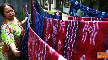 Citizen6, Banjarmasin: Seorang pengrajin menjemur kain sasirangan yang selesai diwarnai.