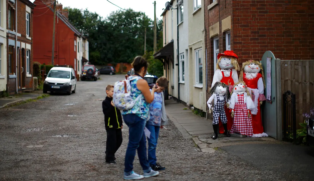 Pengunjung melihat keluarga orang-orangan sawah saat Festival Scarecrow di Heather, Inggris, 28 Juli 2015. Festival sejak 1999 ini selalu menarik perhatian wisatawan mancanegera  untuk berdatangan ke Inggris. (REUTERS/Darren Staples)