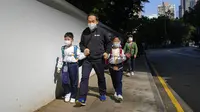 Siswa sekolah dasar berjalan di Hong Kong, Selasa (11/1/2022). Dalam upaya membatasi penularan COVID-19 varian Omicron, Hong Kong mengumumkan penutupan taman kanak-kanak (TK) dan sekolah dasar (SD) setelah infeksi dilaporkan terjadi di kalangan siswa. (AP Photo/Kin Cheung)