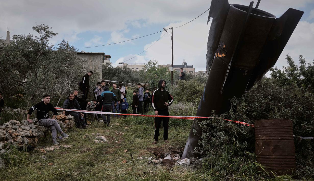 Warga Palestina berkumpul di sekitar puing-puing rudal Iran yang jatuh di desa Kifl Haris, Tepi Barat, Selasa, 24 Maret 2026. (AP Photo/Majdi Mohammed)