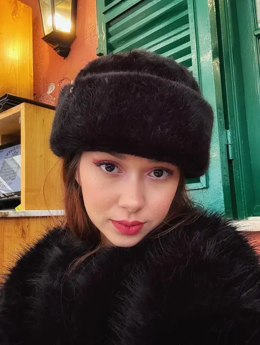 Di foto tersebut, Rebecca Klopper mengenakan baju musim dingin bernuansa hitam. Lengkap dengan headpiece berbulu yang menutupi rambut kemerahannya. [@rklopper]