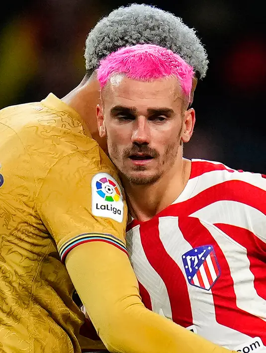 Pemain Atletico Madrid Antoine Griezmann (kanan) berpelukan dengan pemain Barcelona Ronald Araujo usai pertandingan sepak bola La Liga Spanyol di Stadion Civitas Metropolitano, Madrid, Spanyol, 8 Januari 2023. Antoine Griezmann tampil dengan gaya rambut baru berwarna pink bersama Atletico Madrid. (AP Photo/Manu Fernandez)