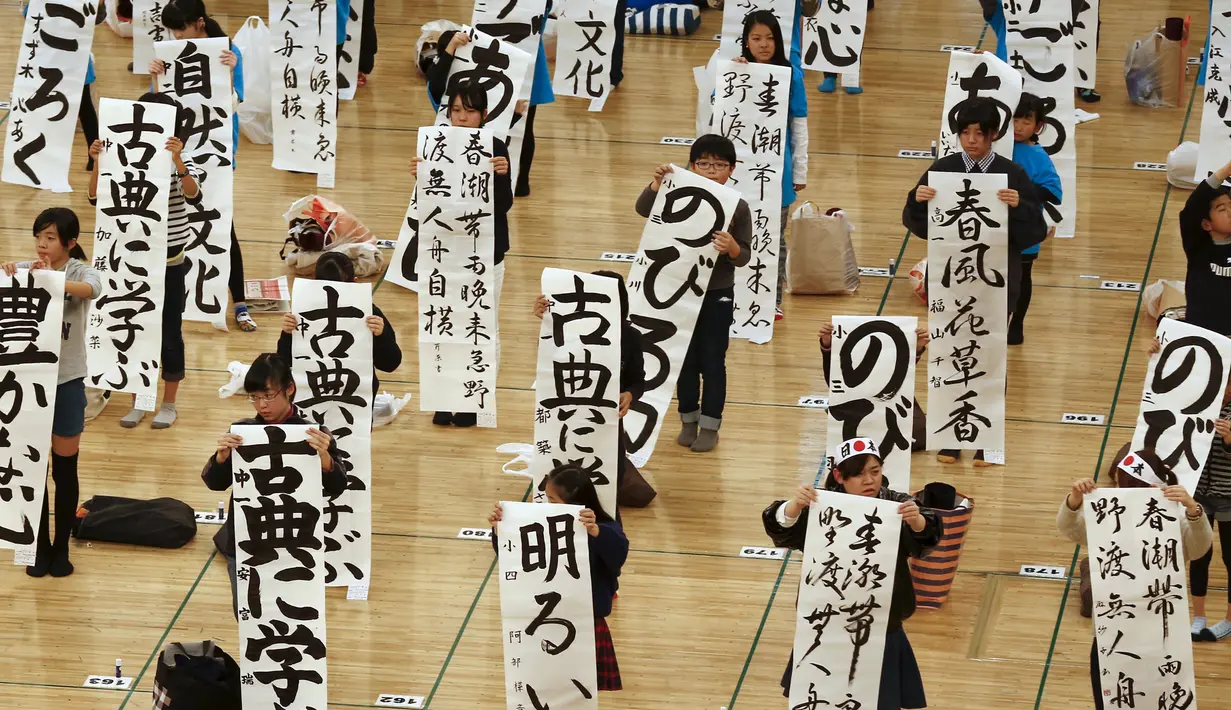 Siswa memperlihatkan tulisan mereka saat mengikuti kontes kaligrafi dalam merayakan tahun baru di Tokyo, Jepang, Selasa (5/1/2016). Lebih dari 3000 peserta menuliskan resolusi tahun baru di atas sebuah kanvas. (REUTERS / Thomas Peter)