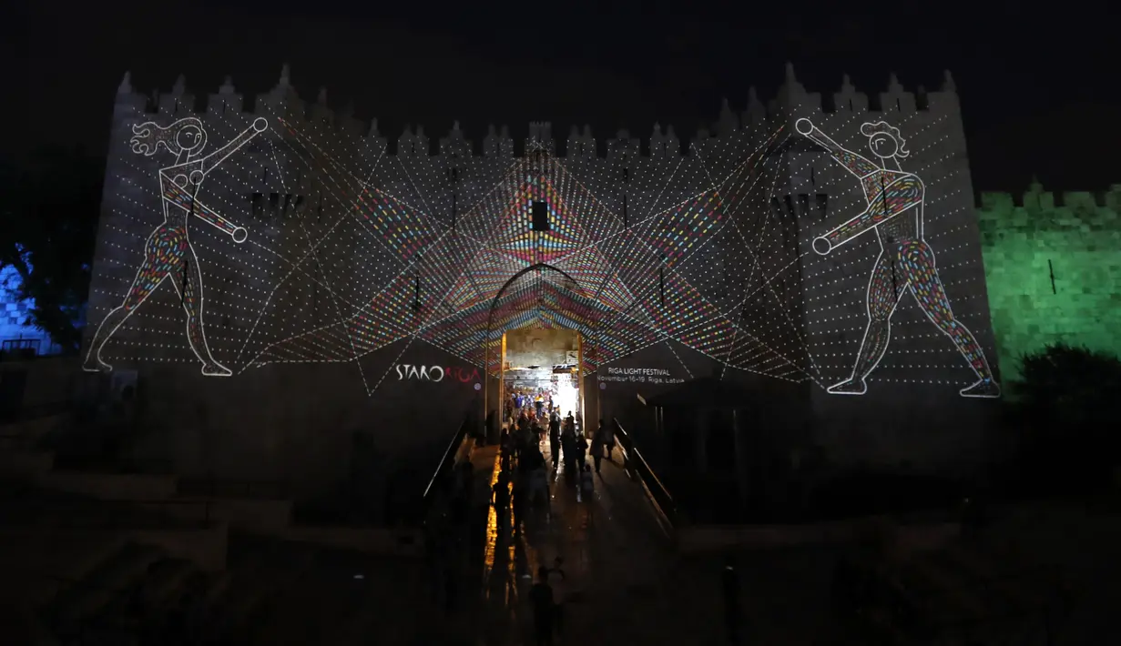 Orang-orang berjalan di dekat gerbang Damaskus selama festival cahaya di kota tua Yerusalem, 28 Juni 2018. Dalam festival yang ke-10 ini, baik anak maupun dewasa bisa datang tanpa dipungut biaya. (AFP / Ahmad GHARABLI)